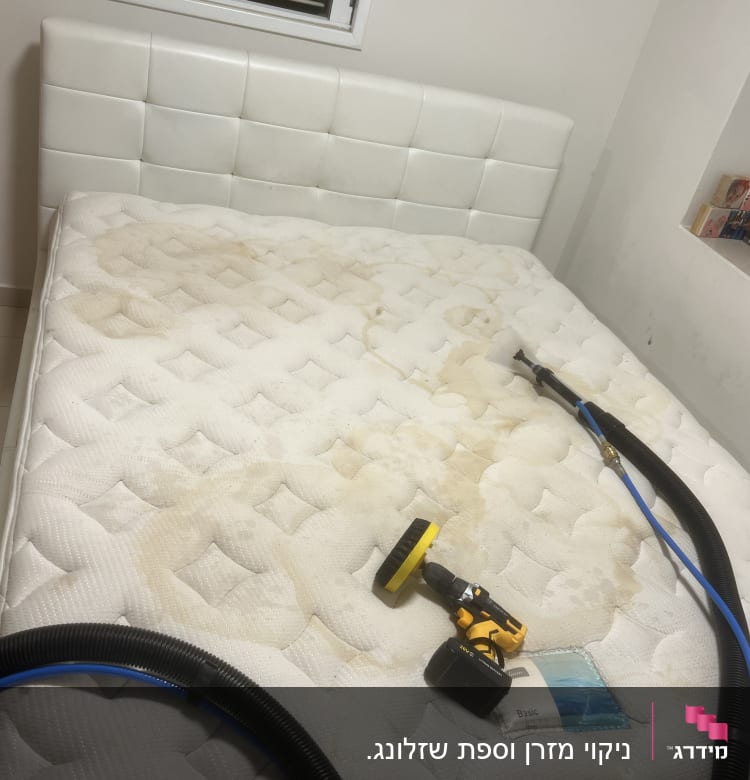 מזרן עם כתמים, מכונת ניקוי צהובה וצינור שחור